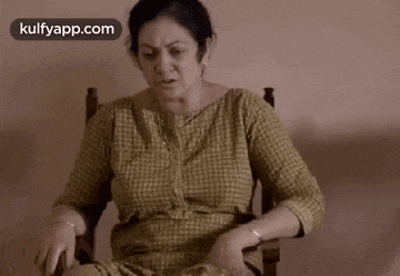 a woman is sitting in a chair making a funny face and making a funny face .