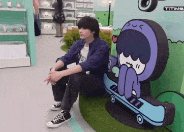 a man sits next to a statue of a person on a skateboard and a sign that says t-time