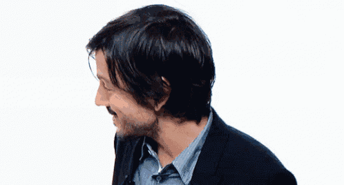 a man with a beard wearing a suit and a blue shirt is smiling