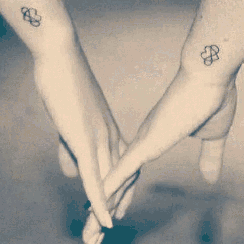 a couple of people with matching tattoos on their wrists .