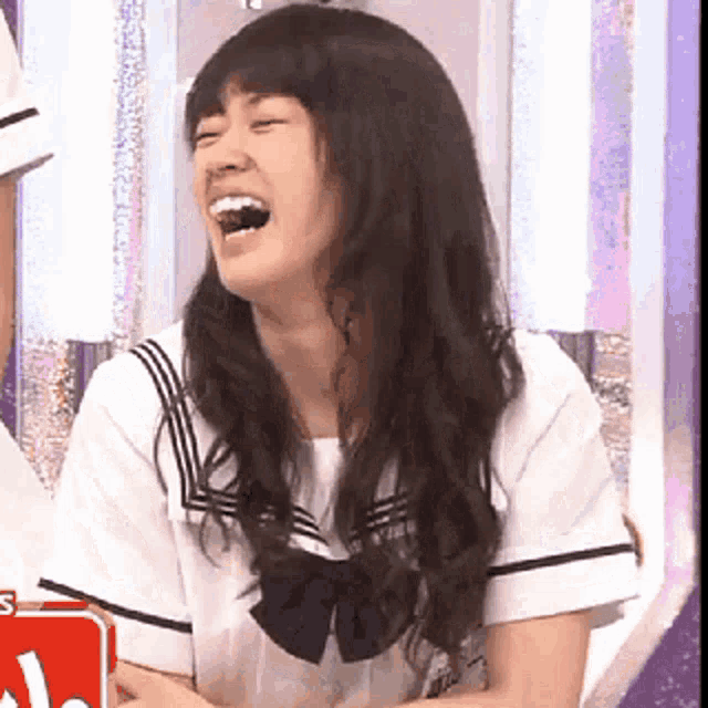 a girl in a school uniform is laughing with her mouth wide open .