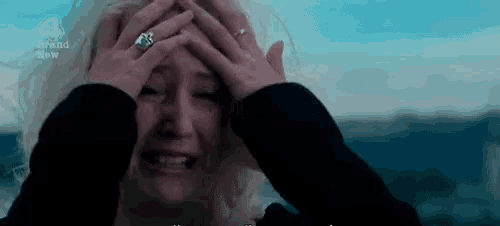 a woman with a ring on her finger is crying and holding her head .