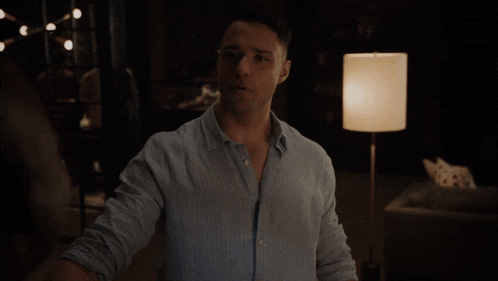 a man standing in front of a lamp in a dark room