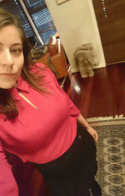 a woman in a pink shirt takes a selfie in a living room