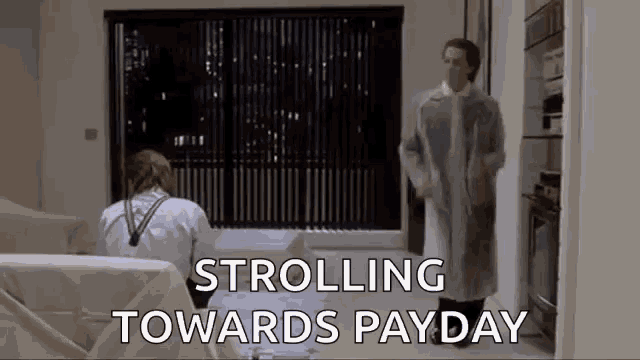 a man in a lab coat is walking towards a woman on a couch .