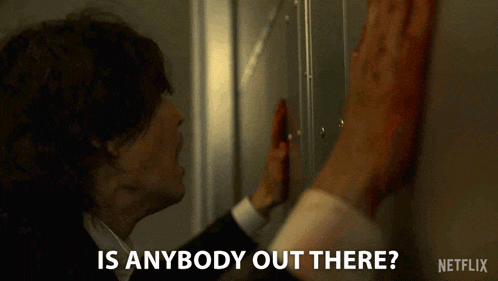a man in a suit is leaning against a wall and asking if there is anybody out there .