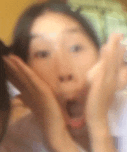 a blurry picture of a woman 's face with her hands on her face .