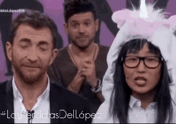 a man and a woman are standing next to each other wearing a unicorn hat .
