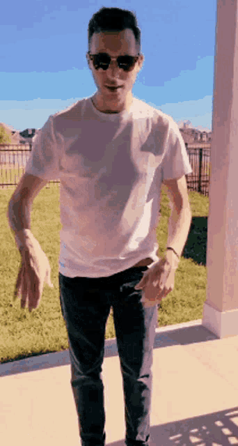 a man wearing sunglasses and a white t-shirt is dancing