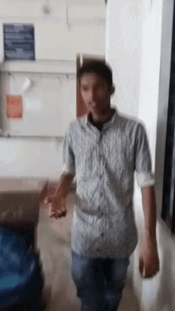 a man in a blue and white shirt is walking in a hallway