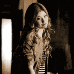 a woman wearing a striped shirt and a denim jacket looks at the camera