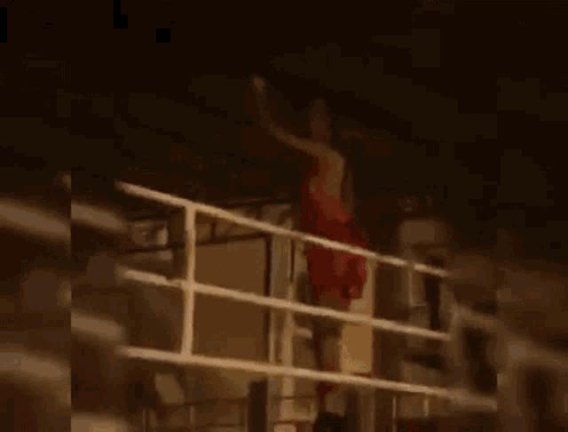 a woman in a red dress is standing on a railing in a room .