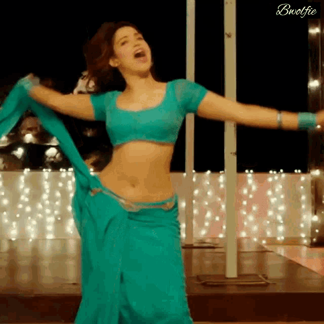 a woman in a blue saree is dancing with her arms outstretched