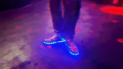 a person wearing glow in the dark shoes is walking on a purple floor