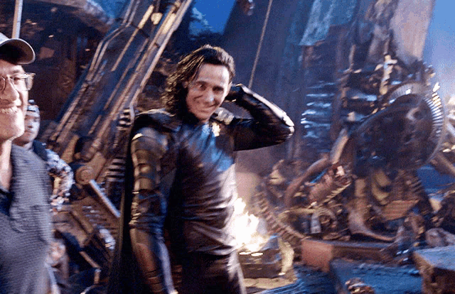 a man in a cap stands next to a man in a leather suit
