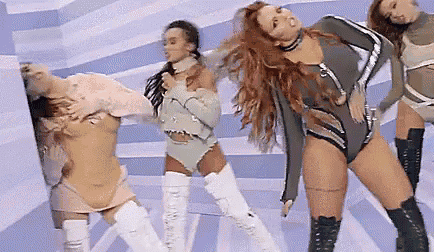 a group of women are dancing together on a stage in a room .