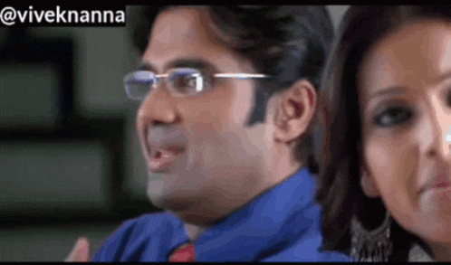 a man wearing glasses and a blue shirt is standing next to a woman ..
