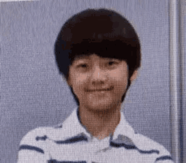a young boy with a striped shirt on is smiling for the camera .