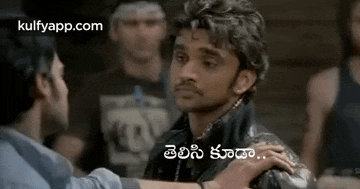 a man in a leather jacket is talking to another man in a crowd .