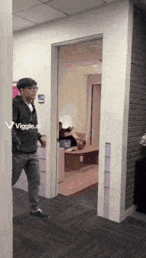 a man in a black jacket is walking through a doorway with a viggle.ai sticker on the wall