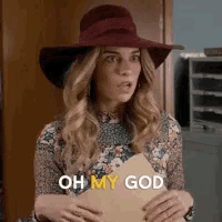 a woman wearing a red hat is holding a piece of paper and saying oh my god .