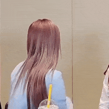 a woman is holding her hair in a ponytail while holding a cup of milkshake .