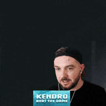 a man covering his face with his hand with a kendra beat the game sign in front of him
