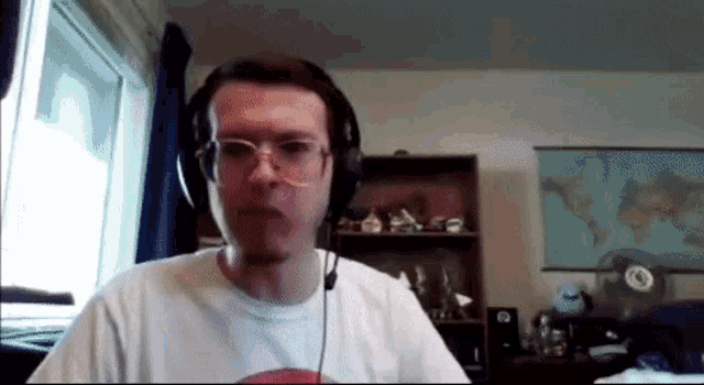 a man wearing glasses and headphones is sitting in front of a map of the world