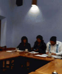 a blurry picture of three people sitting at a table with cups of coffee