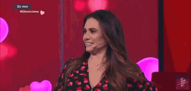 a woman in a red and black dress stands in front of a screen with hearts on it
