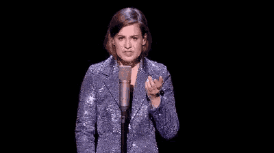 a woman in a blue jacket is standing in front of a microphone .