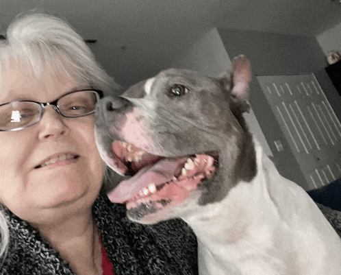 a woman with glasses and a dog with its tongue hanging out