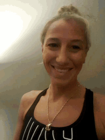 a woman wearing a black tank top with the letter u on it smiles