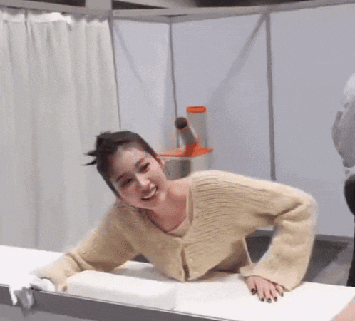 a woman in a tan sweater is laying on a table .