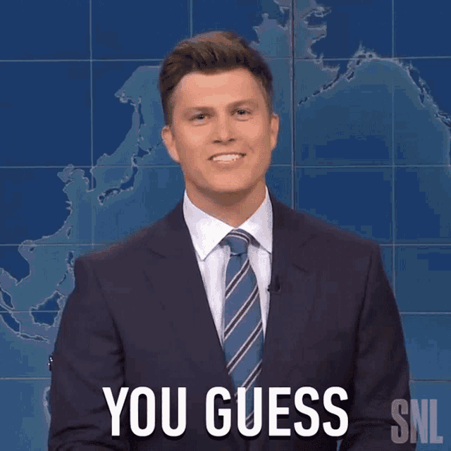 a man in a suit and tie says you guess in front of a map