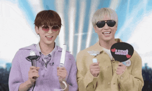 two young men wearing sunglasses and holding a fan with the word lune written on it