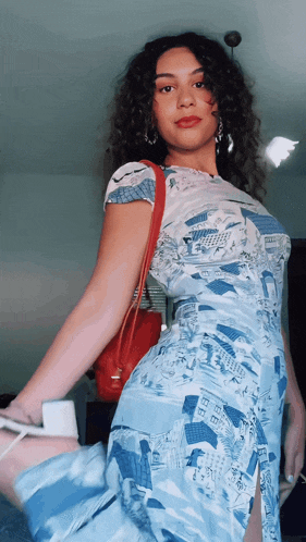 a woman in a blue and white dress has a red purse on her shoulder
