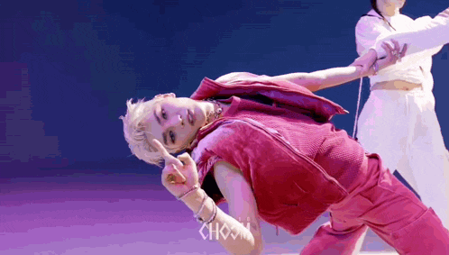 a man in a pink vest is dancing with a woman in a white shirt .