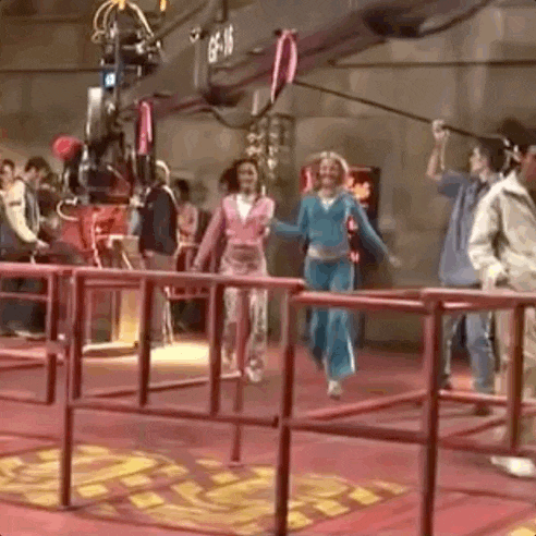 a group of people are standing behind a red fence in a room .