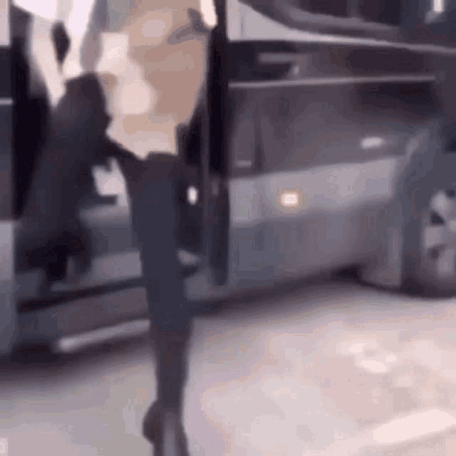a woman is standing next to a bus with her legs crossed .