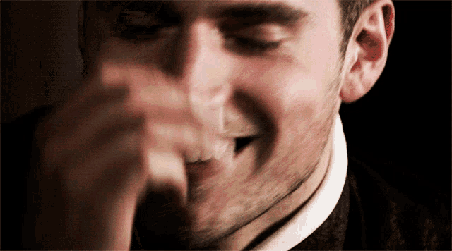 a close up of a man 's face with his hand covering his mouth
