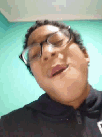 a close up of a person wearing glasses against a blue wall