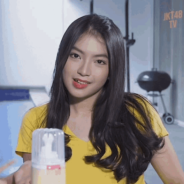 a girl in a yellow shirt is standing in front of a bbq and a sign that says jkt48 tv