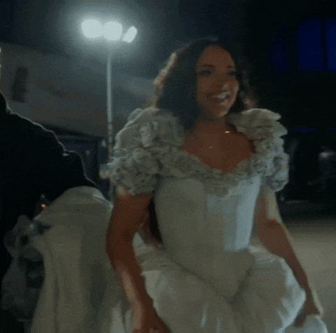 a woman in a white dress with ruffles on the sleeves smiles