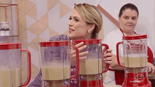 a woman standing next to a blender that says sbt