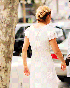a woman in a white dress with ruffled sleeves is walking down a street