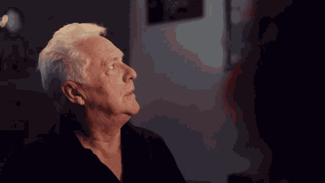 a man with gray hair is looking up at something