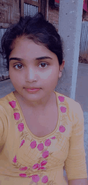 the girl is wearing a yellow shirt with pink flowers on it