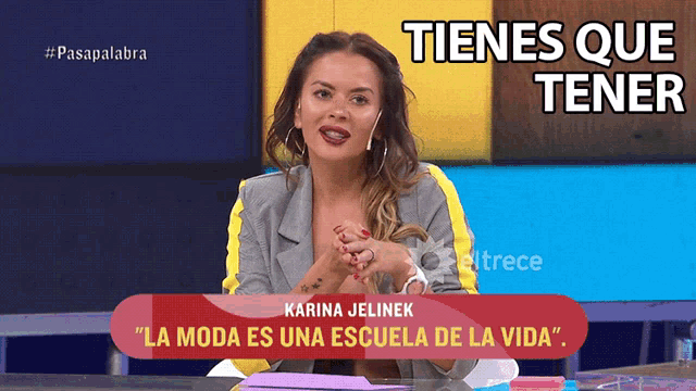 a woman sitting at a table with a sign that says tienes que tener on it