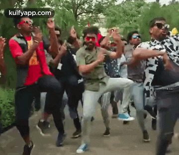 a group of young men are dancing on a street in a park .